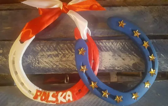 Biało-czerwona podkowa z napisem „Polska” obok niebieskiej podkowy ze złotymi gwiazdami.